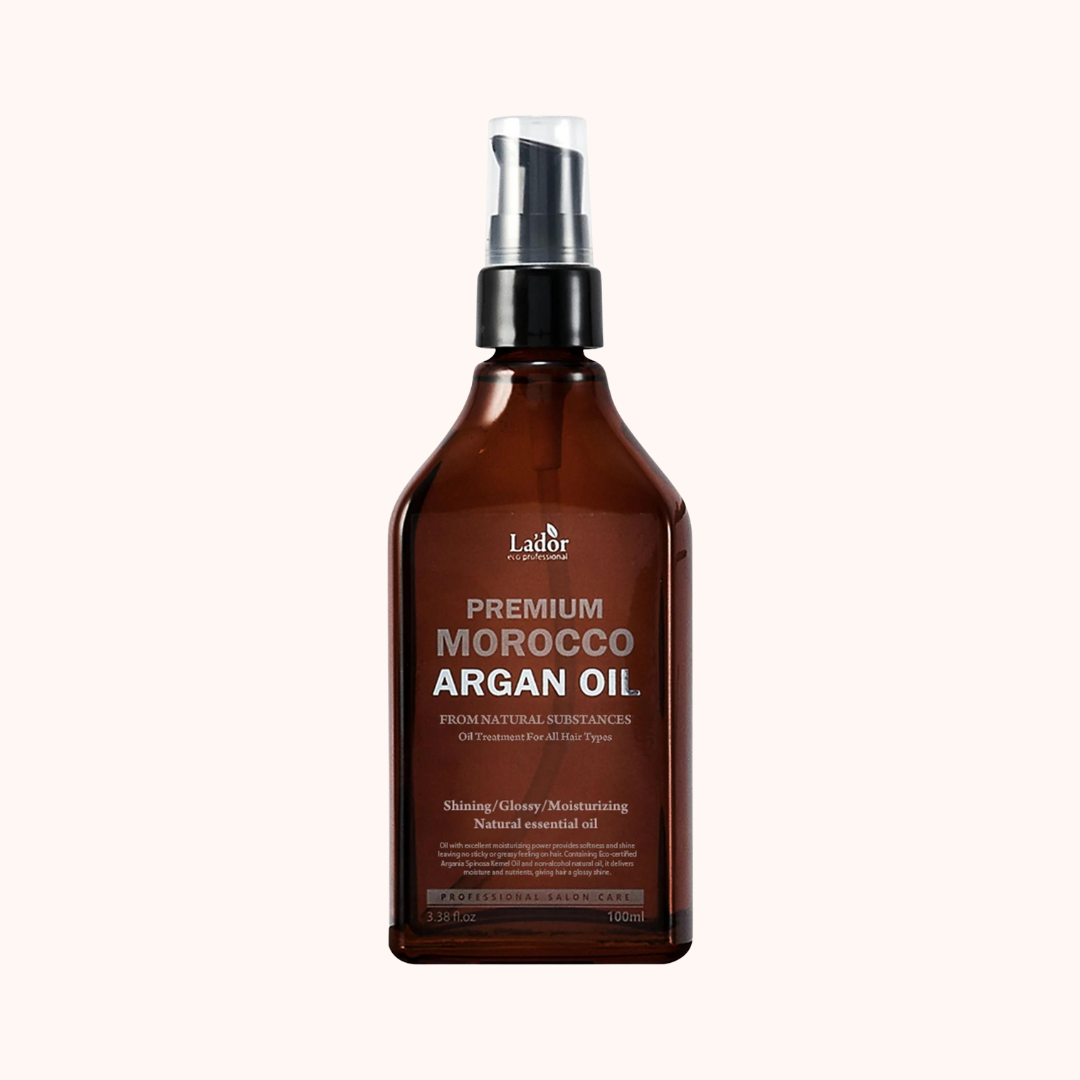 A bottle of Lador Premium Morocco Argan Oil, 100ml, with a spray nozzle, labeled as a hair care product with natural ingredients.