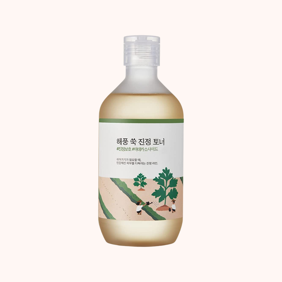 A clear plastic bottle with a pump dispenser containing a yellow-toned Round Lab Mugwort Calming Toner, with Korean and Chinese text labeling.