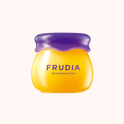 A jar of Frudia Blueberry Hydrating Honey Lip Balm with a purple lid, indicating the product is designed from fruit.
