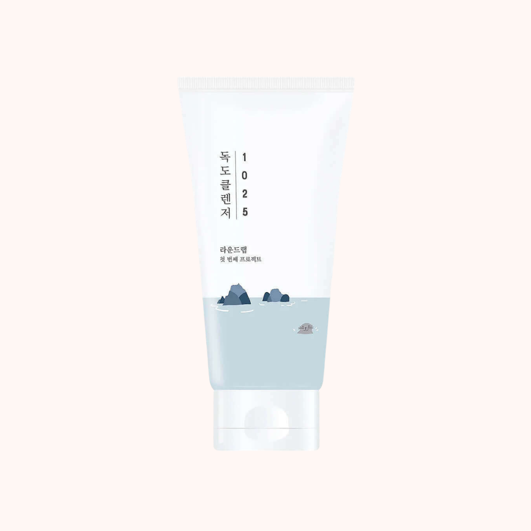 A white skincare tube with Korean text and a minimalist blue mountain-and-water illustration near the bottom, centered on a very light warm beige background.