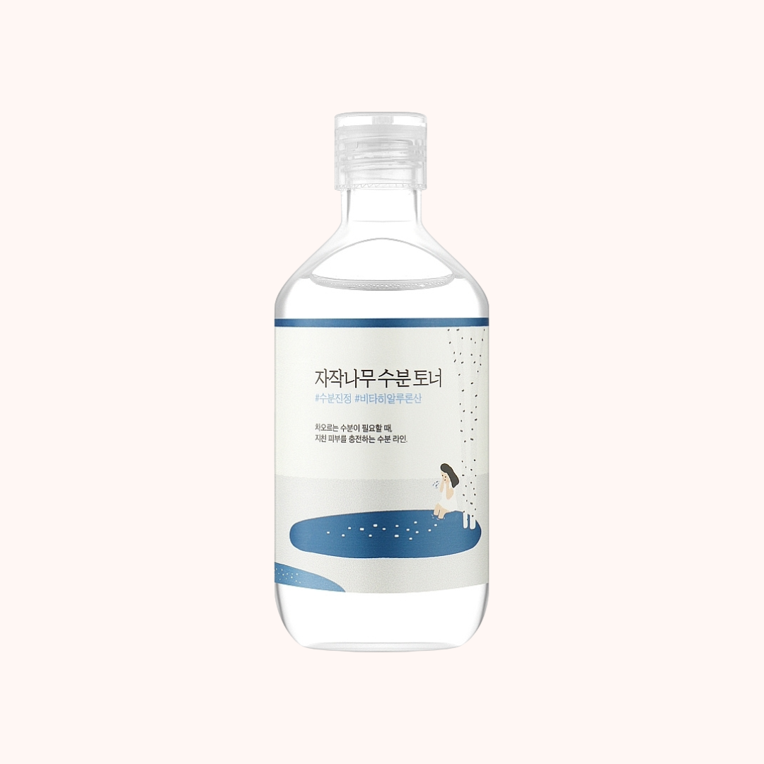 A clear plastic bottle of facial toner with a white and blue label, featuring Korean text and a minimalist illustration of a child sitting by a pool. The bottle is centered on a very light, warm off-white background.